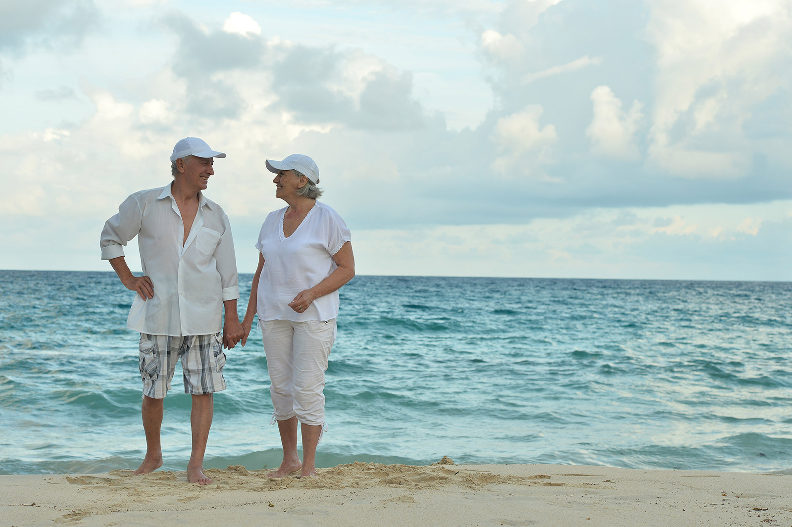 Elder couple holding hands on a beach.